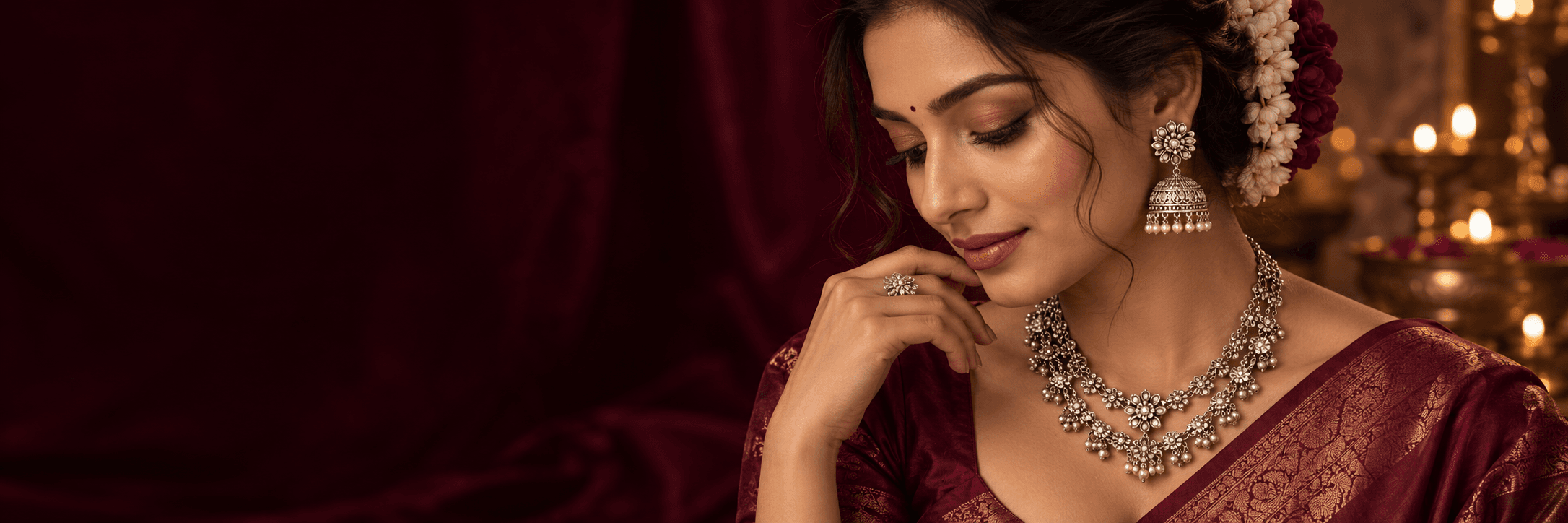 Woman wearing ornate silver earrings and a necklace with burgundy silk and jasmine flowers